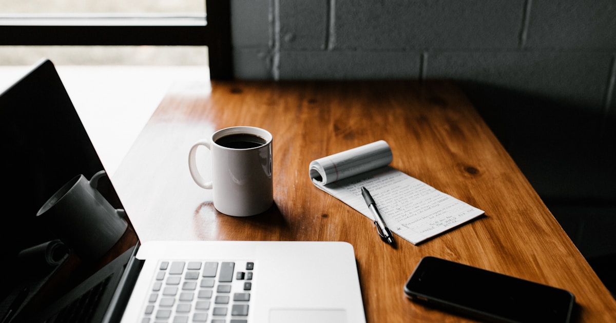 Notebook e xícara de café sobre mesa representando criação de conteúdo